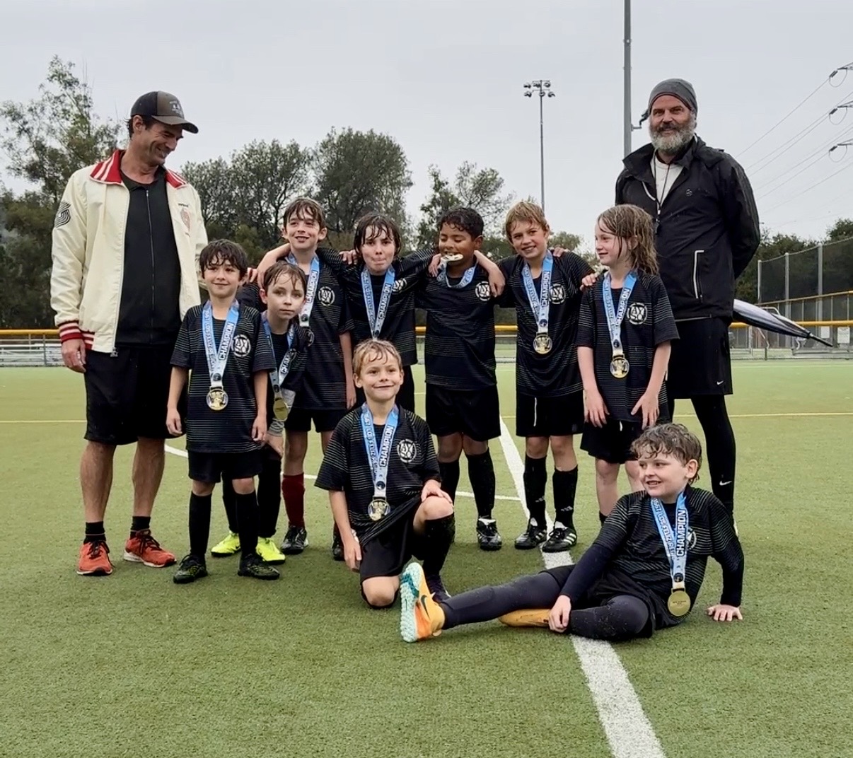 Los Feliz AYSO volunteer coaches with medal-winning players on the field